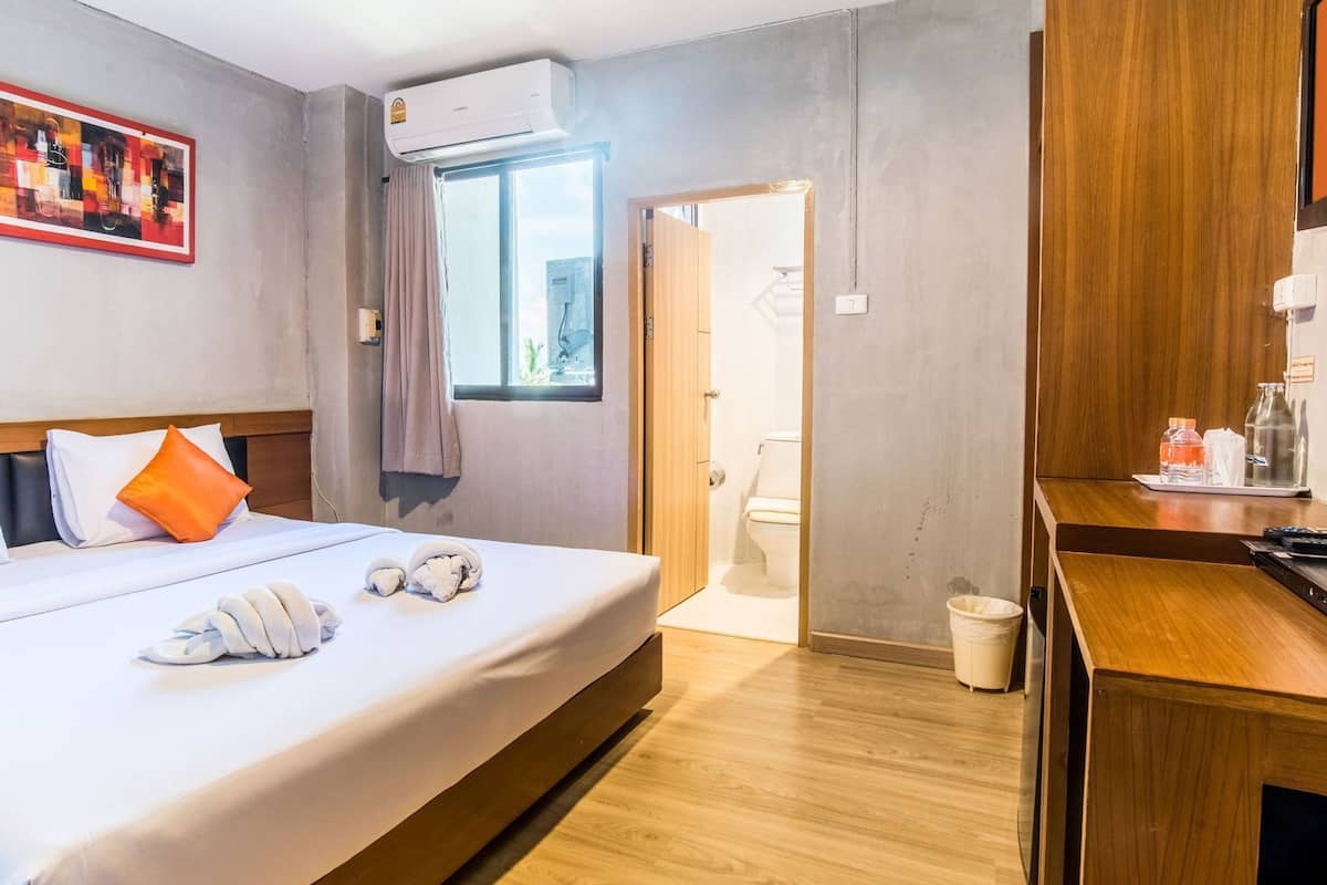 Ein Hotelzimmer mit Bett, Schreibtisch, Fenster, Klimaanlage und einem Bild an der Wand.