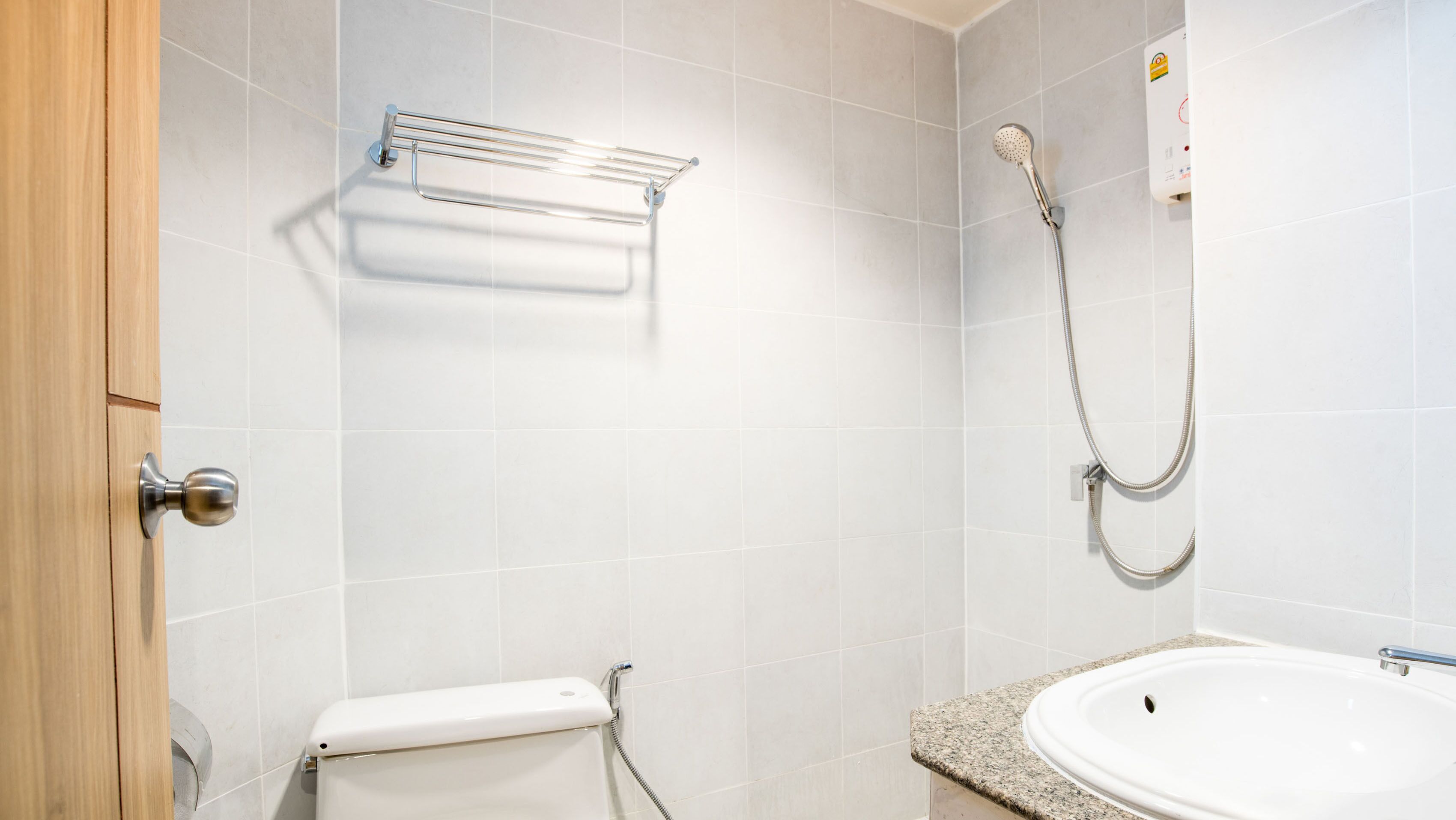 A bathroom with a toilet, sink, shower, and towel rack.