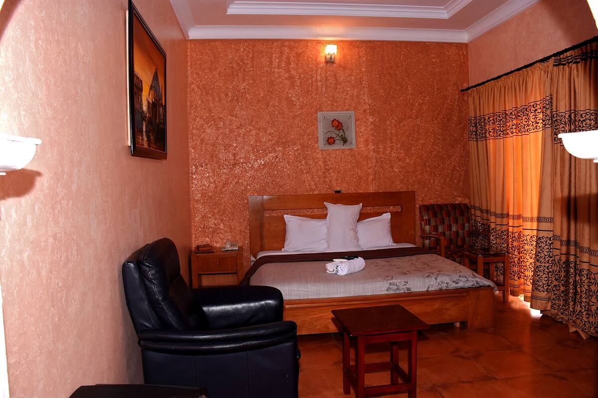 A bedroom with a bed, a chair, a nightstand, and a small table.