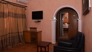 A living room with a TV, a desk, a chair, and a couch. - LaMaison Hotel (Ibadan)