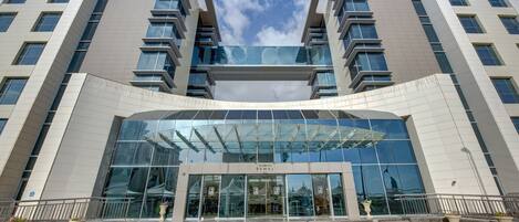 Een modern gebouw met een glazen ingang, meerdere verdiepingen en een heldere lucht.