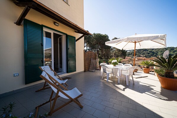 A patio with two lounge chairs, a table with chairs, and a large umbrella.