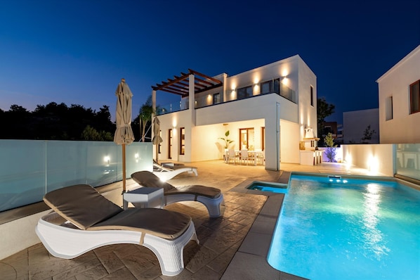 Une maison moderne à deux étages dotée d’une piscine, d’un espace salon extérieur et d’une pergola.
