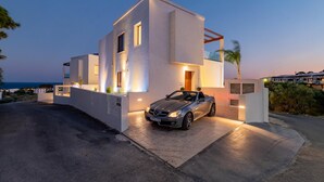 Ett modernt hus med en cabriolet parkerad framför.