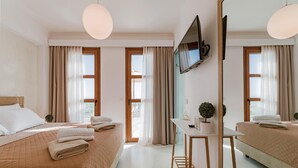 Ett hotellrum med två sängar, ett skrivbord, en TV och en stor spegel.