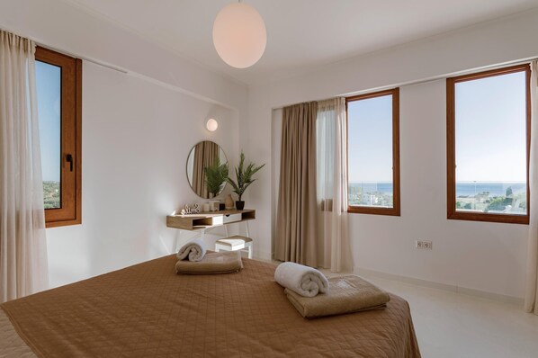 Un dormitorio con una cama grande, una mesita de noche, un espejo, una planta en maceta y vistas a la ciudad.