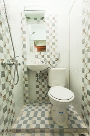 Een badkamer met betegelde vloer, een wastafel, toilet en douche.