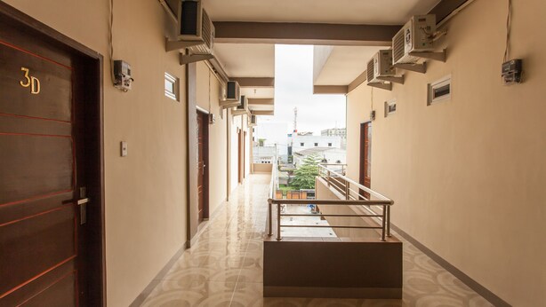 A hotel corridor with a patterned floor, a staircase, and a view of the outside.