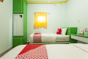 Een hotelkamer met een bed, nachtkastje, spiegel en raam met gordijn.
