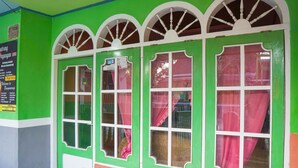 A room with green walls, white-framed windows, and a wooden bench.