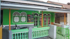 A building with green walls and windows, a motorcycle parked outside, and a signboard.