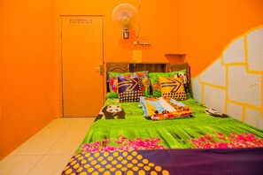 A room with a bed covered in green bedding, colorful pillows, and a panda-themed blanket.