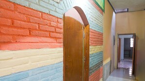 A hallway with a wooden door and a colorful brick wall.