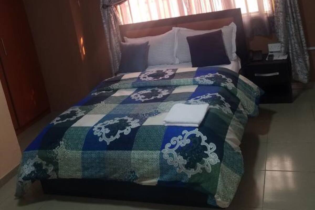 A bedroom with a large bed, a nightstand, and a window with curtains.