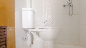 A white toilet with a bidet attachment in a bathroom with white tiled walls. - Hotel O Kina Family Residence Syariah (Malang)