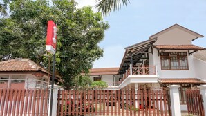 A two-story house with a gated entrance, a balcony, and a red and white sign. - Hotel O Kina Family Residence Syariah (Malang)