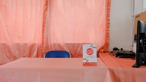 A conference room with a table covered by a pink tablecloth, a blue chair, and a Samsung monitor on a stand. - Hotel O Kina Family Residence Syariah (Malang)