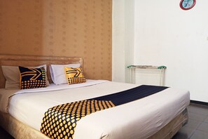 A neatly made bed with patterned pillows and a dark throw blanket. - Hotel O Wisma Hulubalang (Palembang)
