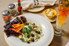 Une assiette de salade composée de différentes variétés de légumes verts, accompagnée d’un verre de thé glacé.