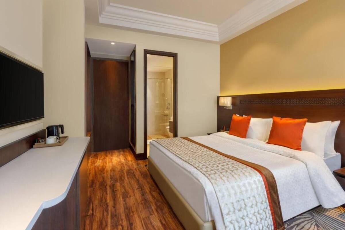 Een hotelkamer met een bed, een televisie, een bureau en een inloopkast.