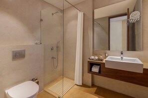 Une salle de bain moderne avec une douche à parois de verre, des toilettes blanches et un lavabo avec un miroir au-dessus.