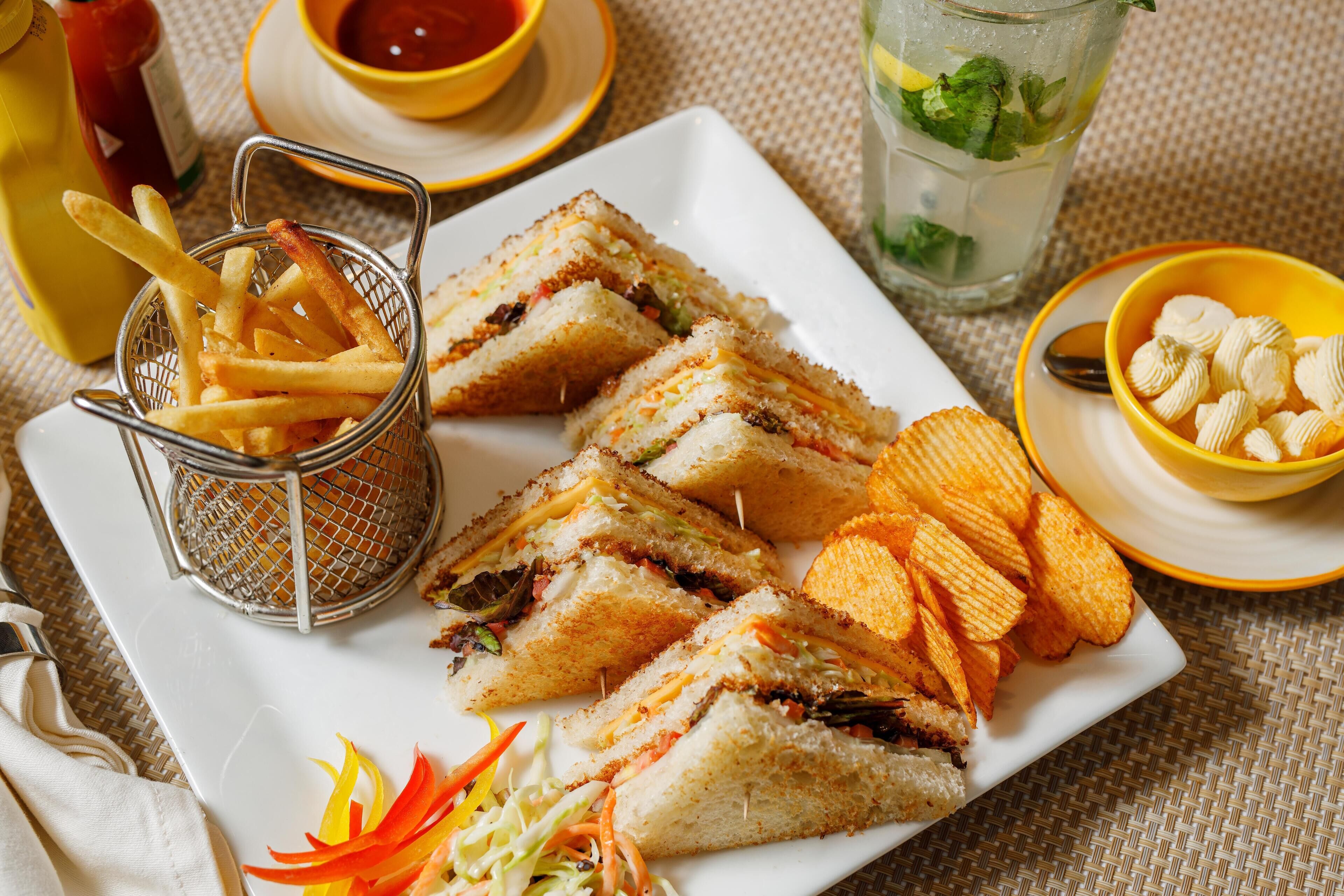 A plate of sandwiches, French fries, and chips.