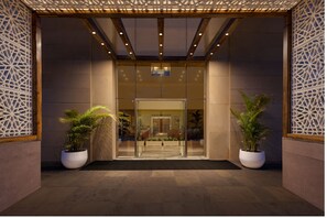 Un hall d’entrée moderne avec une porte en verre, un plafond en bois et des panneaux décoratifs.