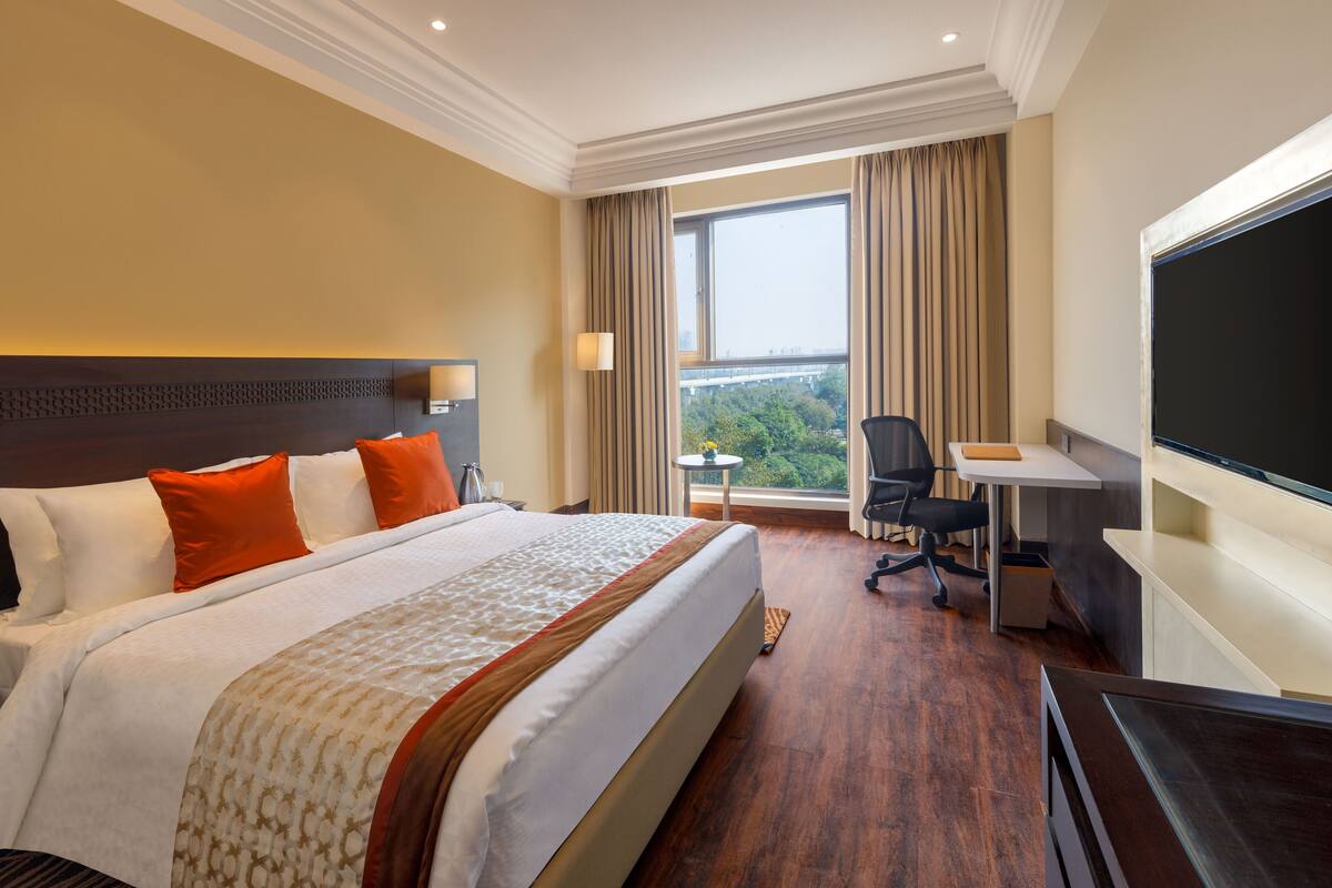 Een hotelkamer met een groot bed, een bureau, een stoel en een televisie.