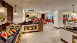 A modern breakfast area with a buffet setup, seating arrangements, and a view of the outdoors. - Ginger Greater Noida Pari Chowk (Greater Noida)