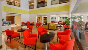 A spacious lobby with multiple seating areas, a central dining space, and a glass-enclosed balcony. - Ginger Greater Noida Pari Chowk (Greater Noida)