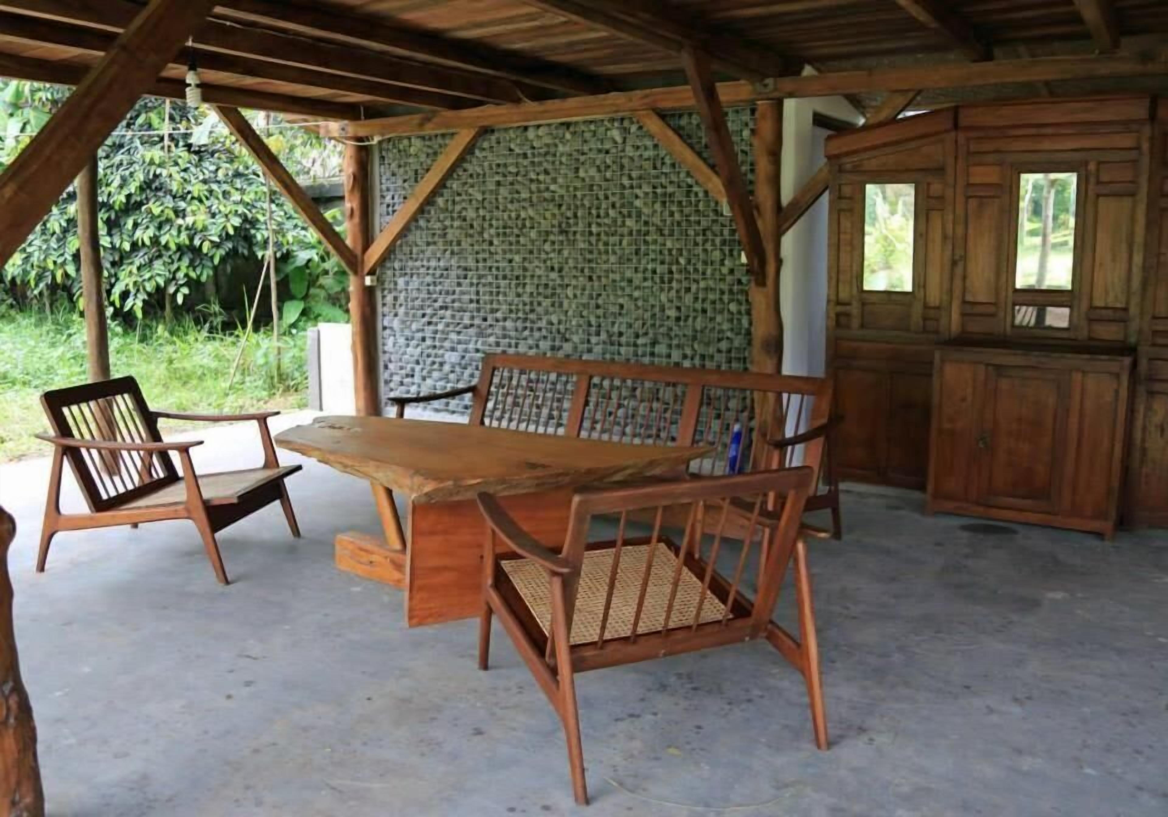 A rustic wooden table and chairs under a covered area with a brick wall and wooden cabinets.