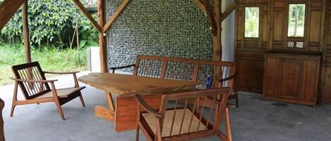 A rustic wooden table and chairs under a covered area with a brick wall and wooden cabinets.