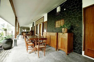 Un espacio de comedor al aire libre cubierto con pared de piedra, muebles de madera y plantas en macetas.