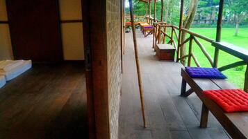 A wooden deck with benches and a view of a lush green garden.