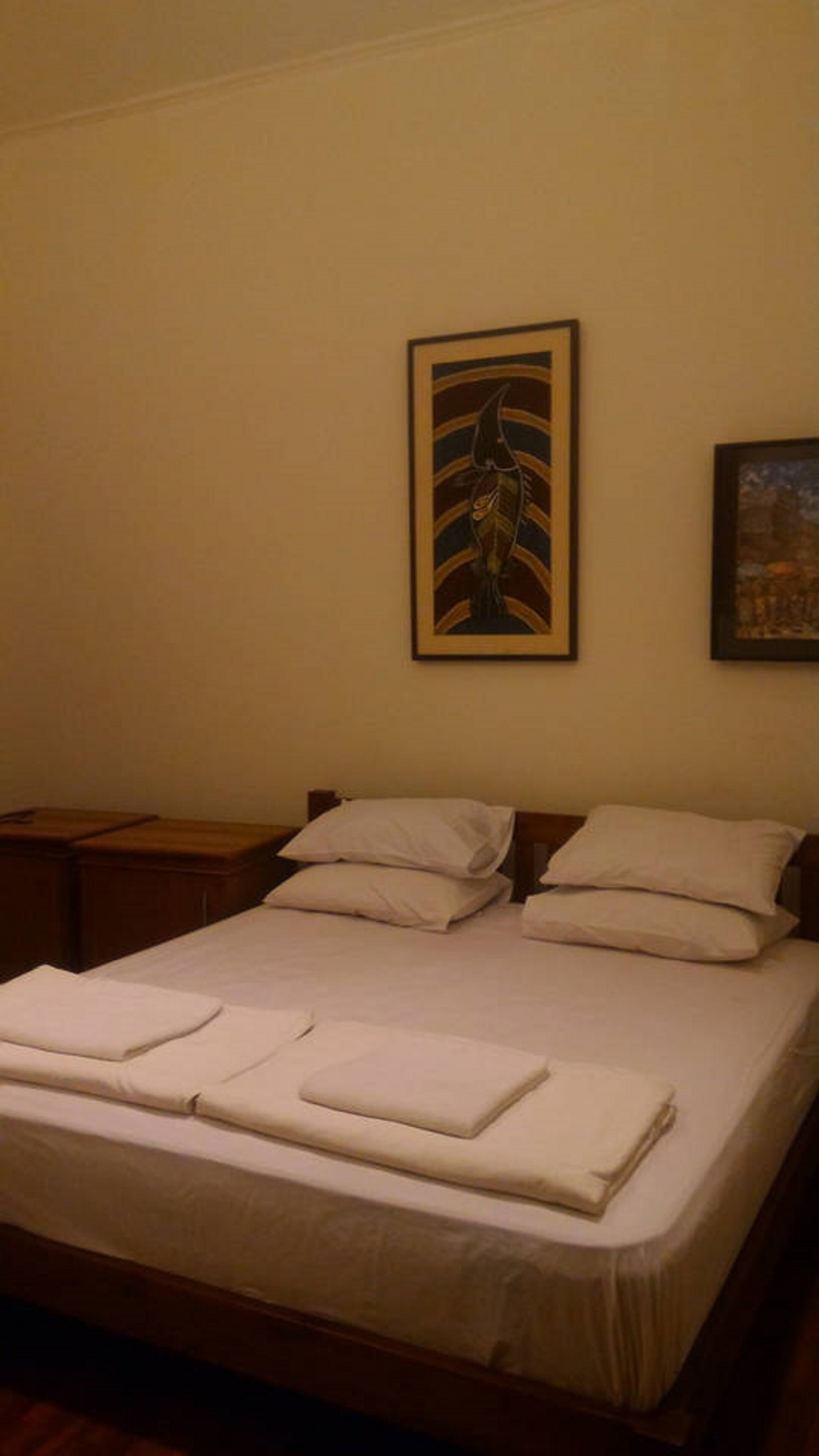 A neatly made bed with pillows and a folded blanket in a room with plain walls.