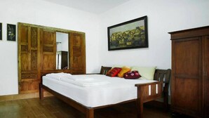 A bedroom with a wooden bed, a wardrobe, and a painting on the wall. - Ronia Mountain Villa Lembang (Lembang)