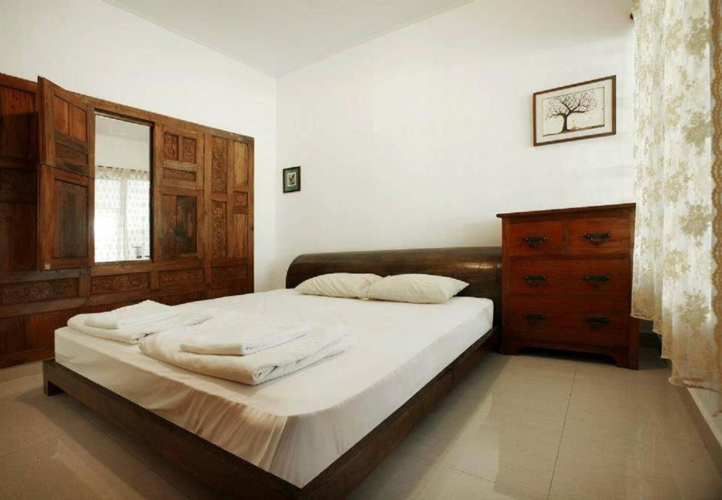 A bedroom with a wooden bed, a dresser, a mirror, and a framed picture on the wall.