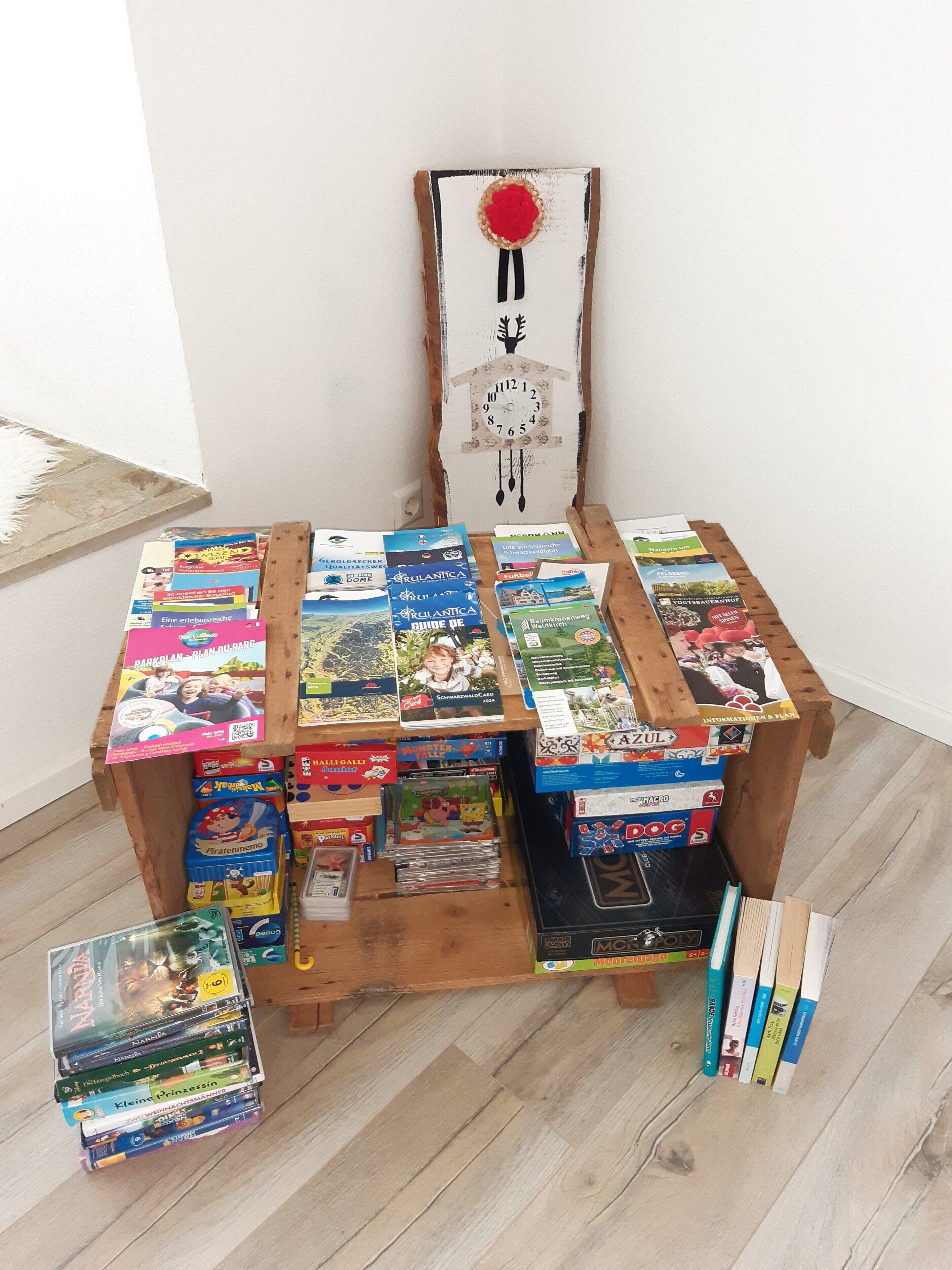 Une table en bois, sur laquelle on trouve divers jeux de société et des livres.