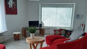Uma sala de estar moderna com um sofá vermelho, mesa de centro de madeira e um vaso de planta.