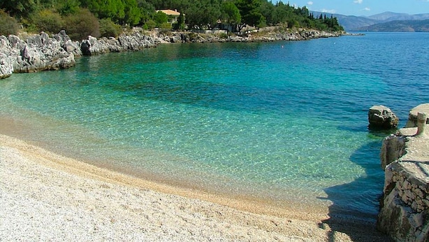 A clear coastal beach with rocky shores and a small building on a hill. - Paleopetres K-One - Premium Double Suite - Sea Views - Beach - Pool - Kalami (Kalami)