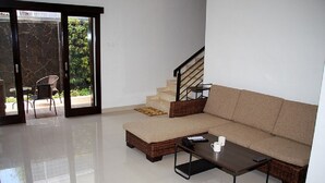 A living room with a sectional sofa, a coffee table, and a staircase. - Rumah Mutiara (Bandung)