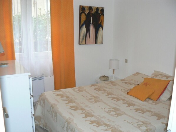 Ein Schlafzimmer mit einem Bett, einem Nachttisch, einer Lampe und einem Bild an der Wand.