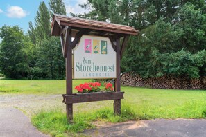 A wooden sign for Zum Storchennest Landhotel with a flower box below.