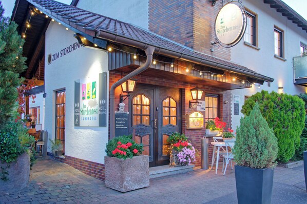 A building with a sign reading "Zum Storchennest Landhotel" and a reception area with a wooden door.