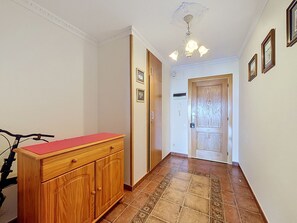 A hallway with a wooden cabinet, a bicycle, and a door leading to another room. - SANT JOAN 3 4 Roses / Roses - INTERimmo (Rosas / Roses)