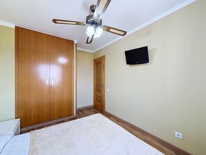 A bedroom with a bed, a wardrobe, a ceiling fan, a television, and a door. - SANT JOAN 3 4 Roses / Roses - INTERimmo (Rosas / Roses)