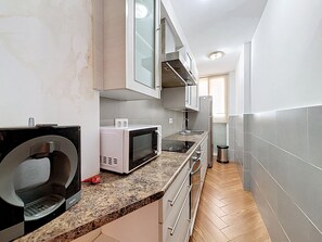 A compact kitchen with a microwave, kettle, and a coffee machine on the counter. - SANT JOAN 3 4 Roses / Roses - INTERimmo (Rosas / Roses)