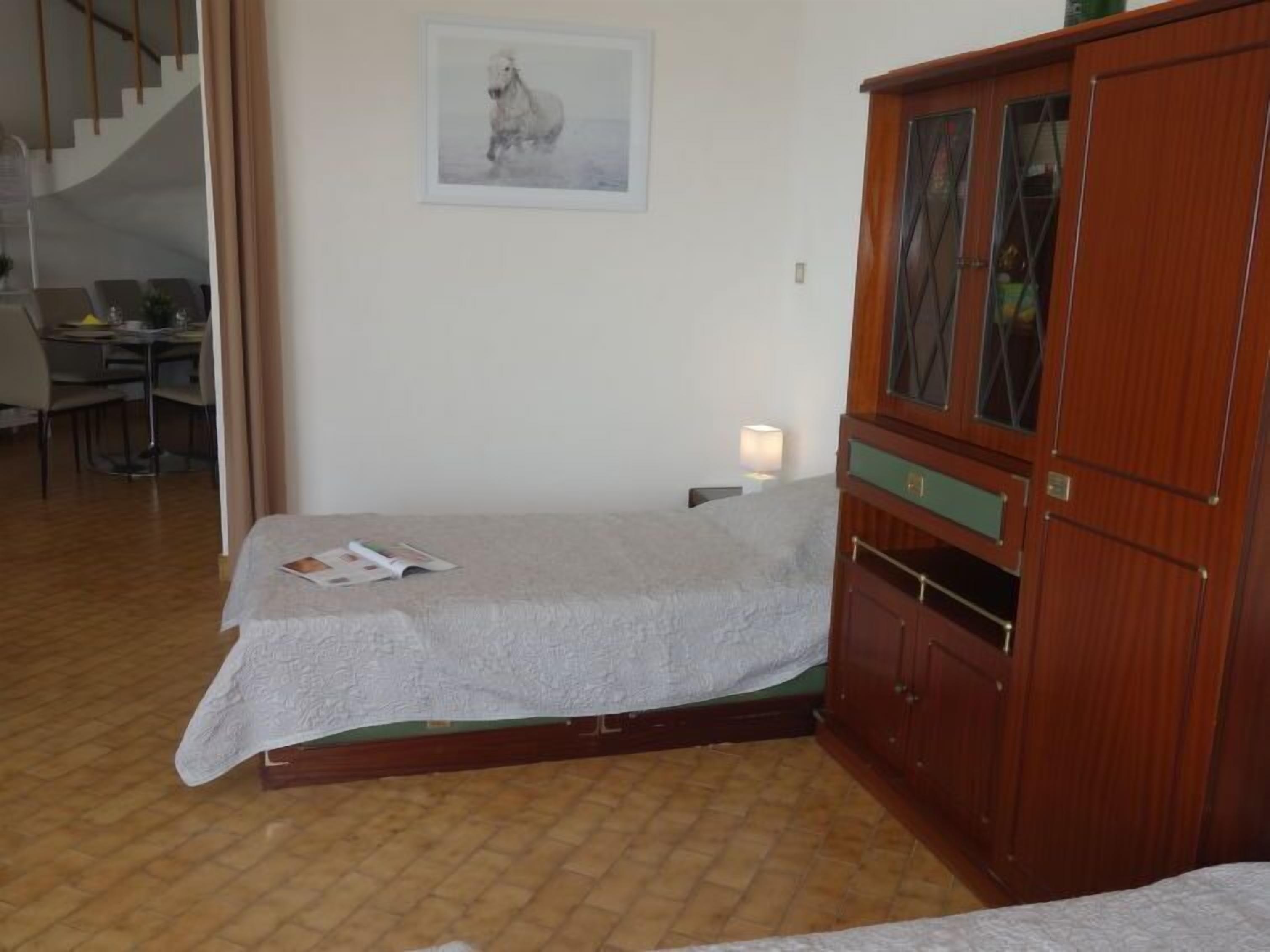 Un dormitorio con cama, un armario de madera, un escritorio y una silla.