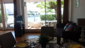 A dining area with a view of a marina, a sofa, and a television in the corner.