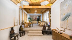 Un interior tradicional con vigas de madera, una escalera central y una pared de galería con obras de arte.